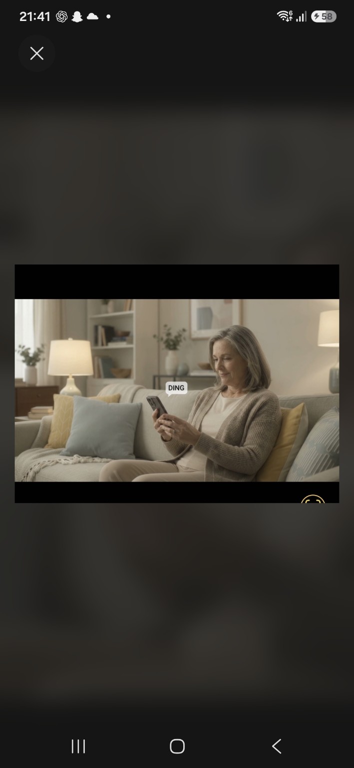 A woman smiling at her phone while sitting comfortably at home