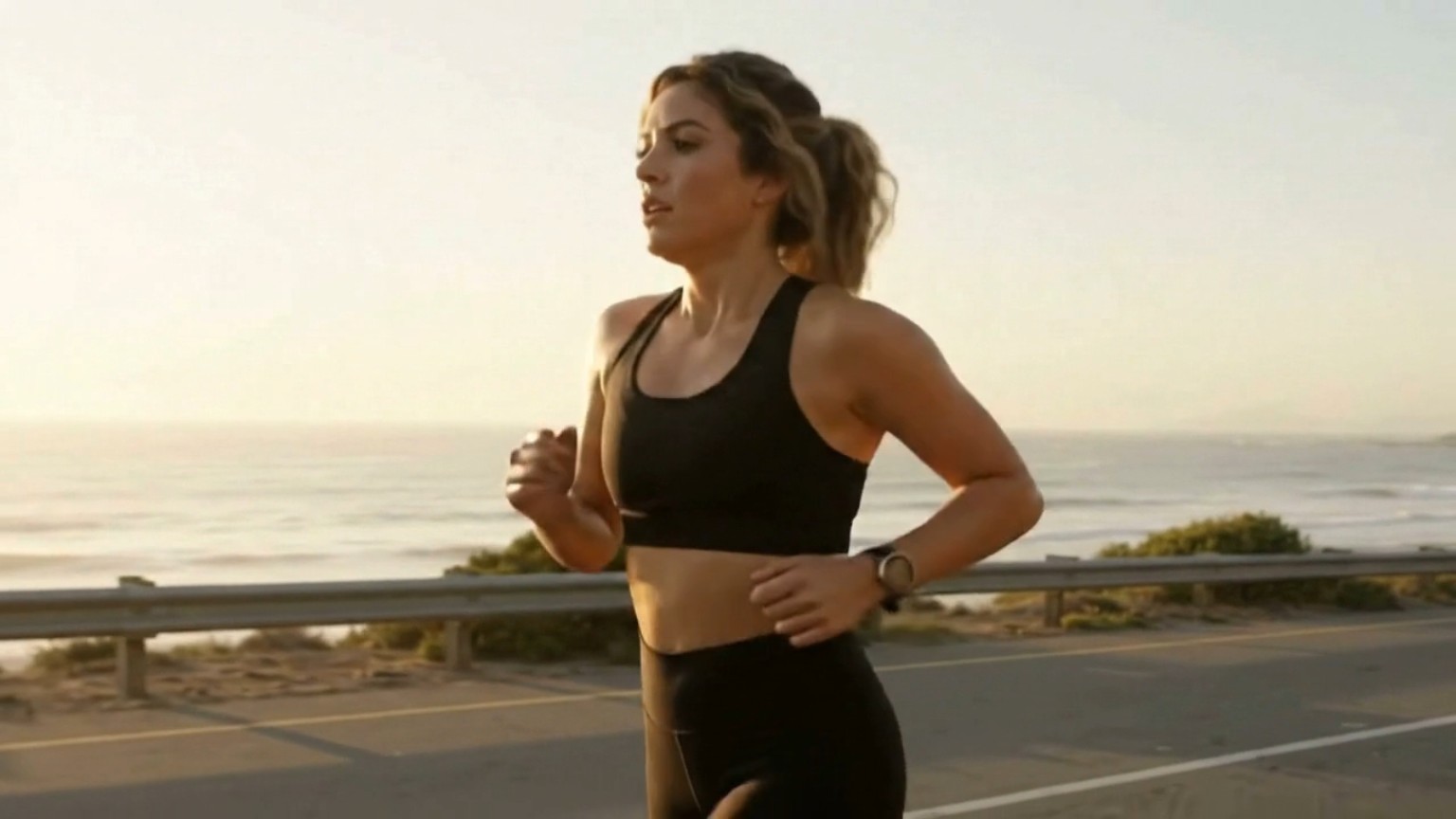 A woman running along the coast in warm evening light